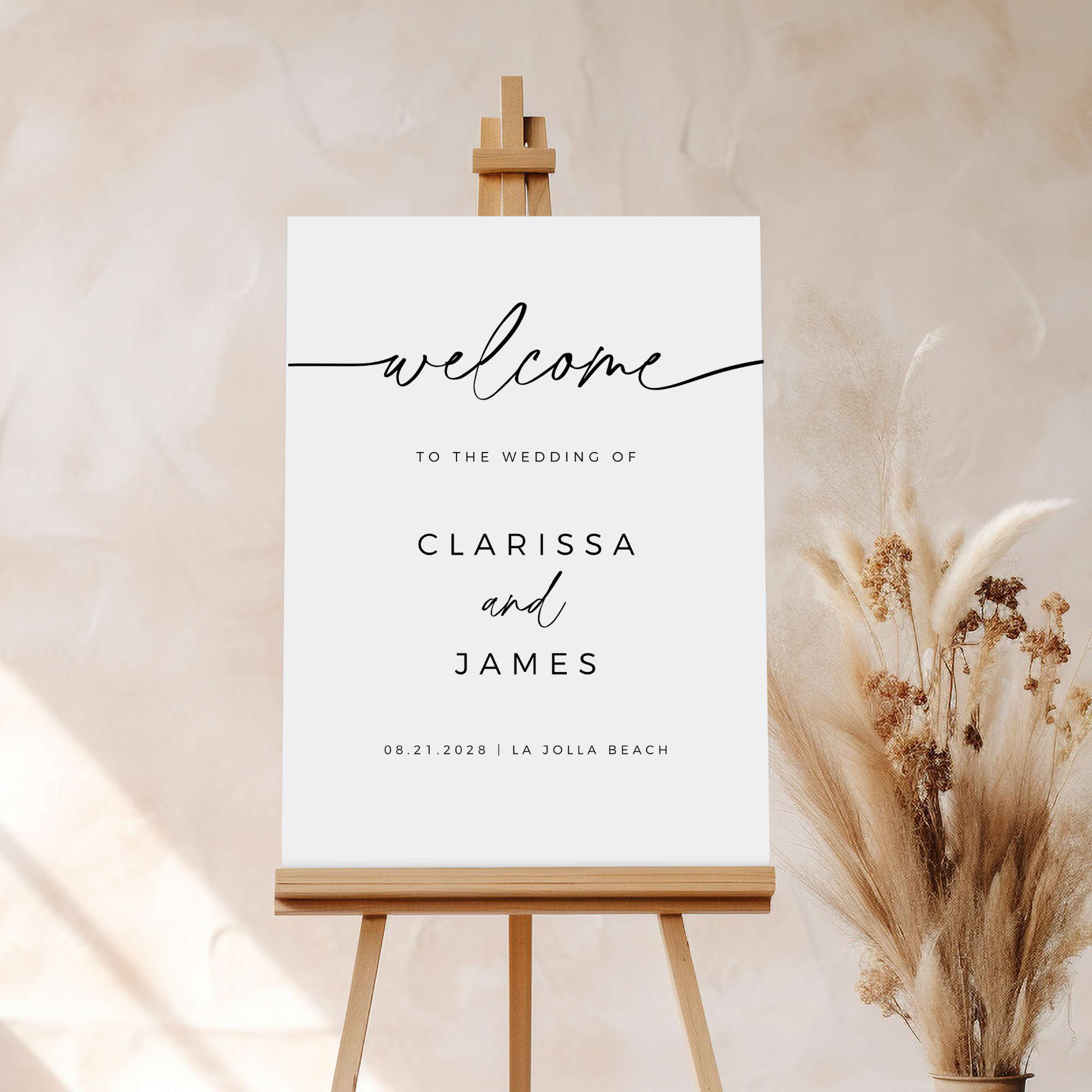 Minimalist wedding welcome sign on an easel with dried plants on a neutral background.
