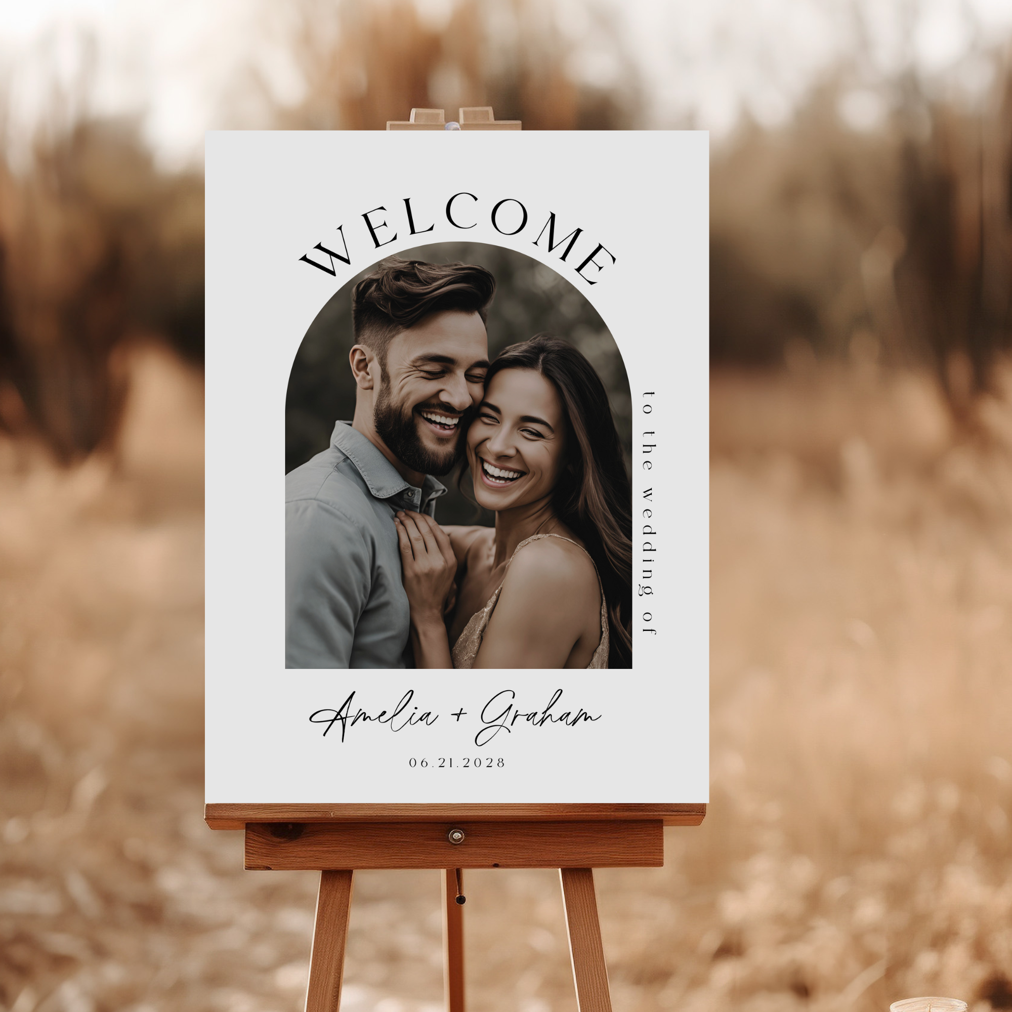 Welcome sign for a wedding with a couple's photo and text on an easel against a blurred natural background.