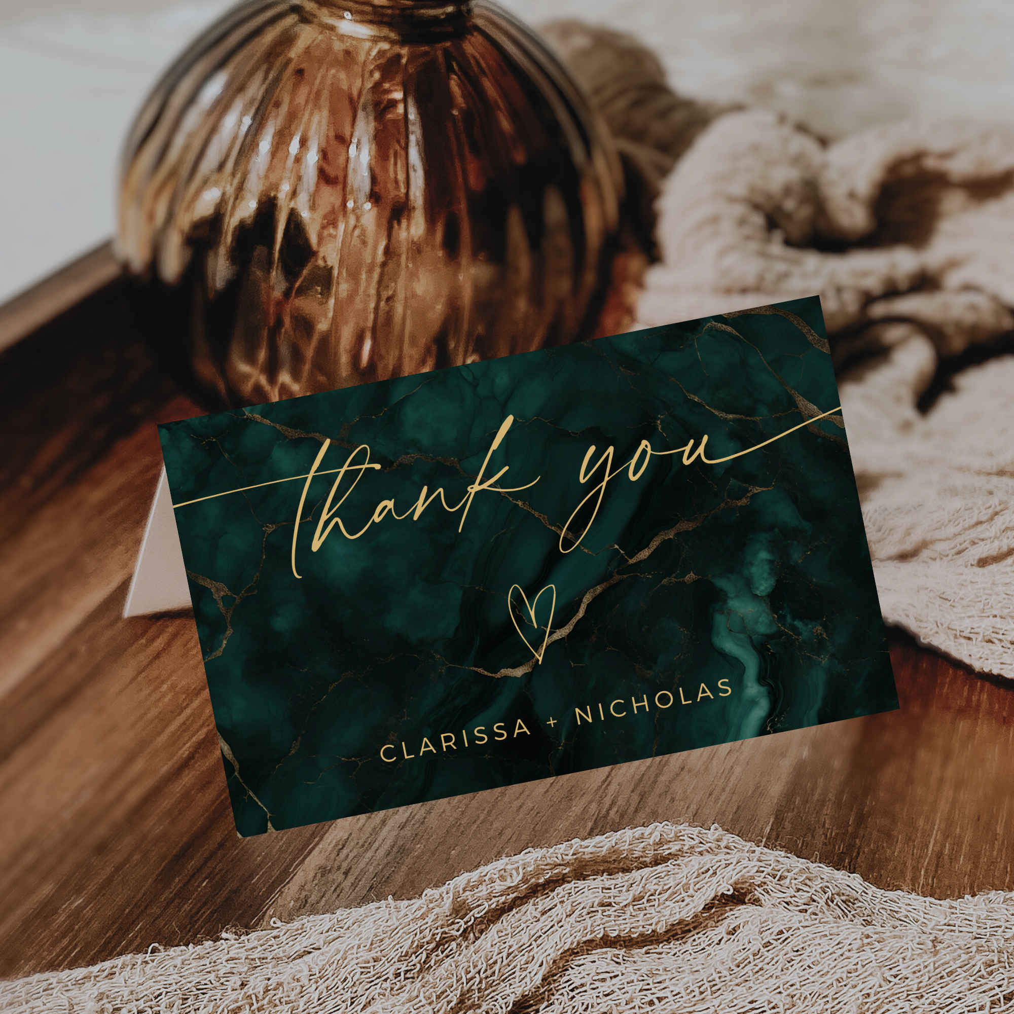 Green marble thank you card with gold text on a wooden surface