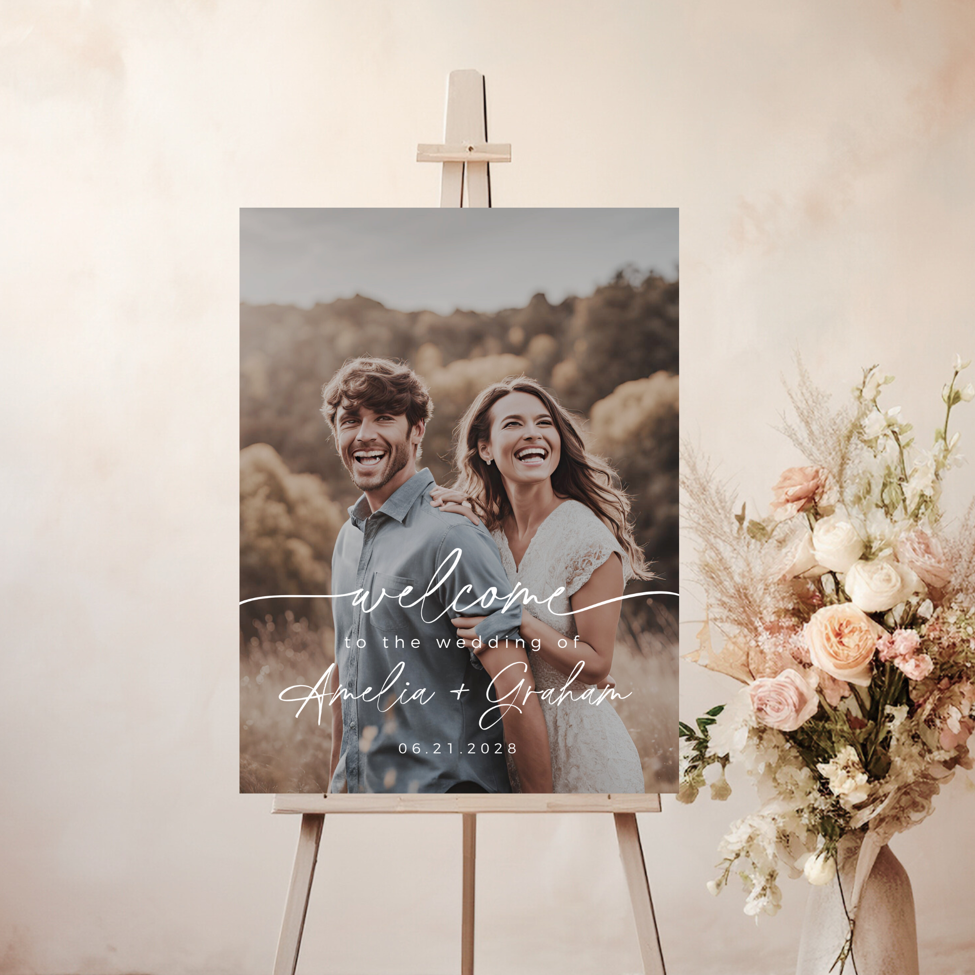 Wedding welcome sign with a couple's photo and text on an easel with flowers.